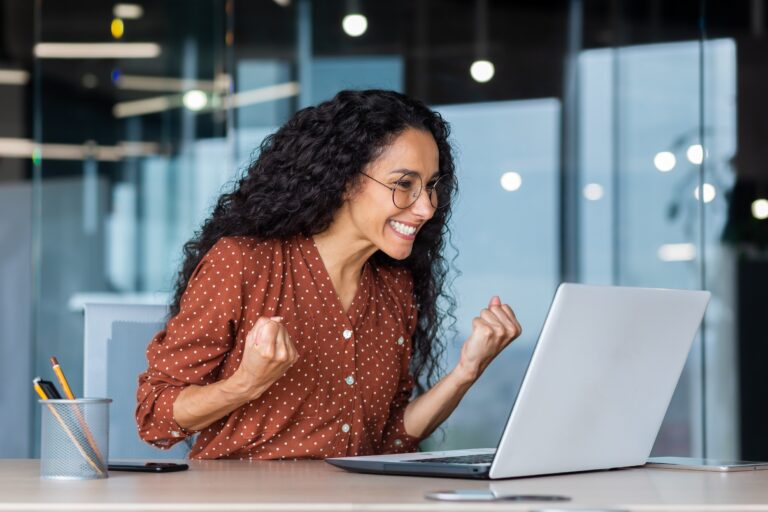 Woman excitedly working on her laptop in an office.
