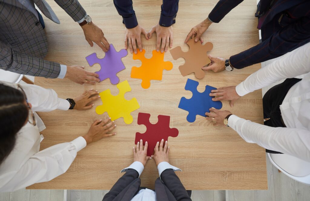 Top view of diverse AP team members brainstorming and attempting to connect puzzle pieces that are all the same shape.