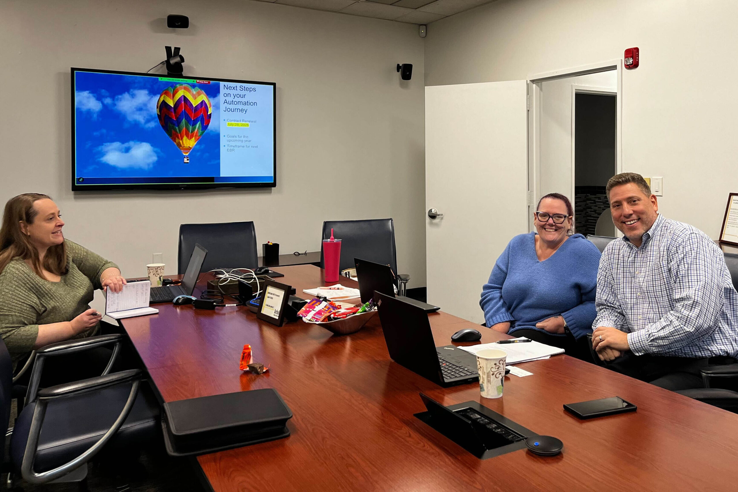 Business executives from Arbill and DataServ sit around a conference table while smiling